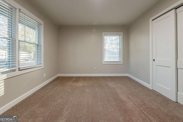 unfurnished bedroom with carpet flooring, a closet, and multiple windows