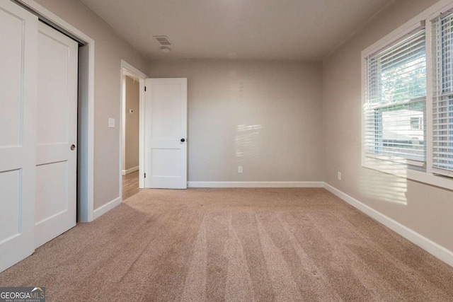 unfurnished bedroom featuring light carpet and a closet