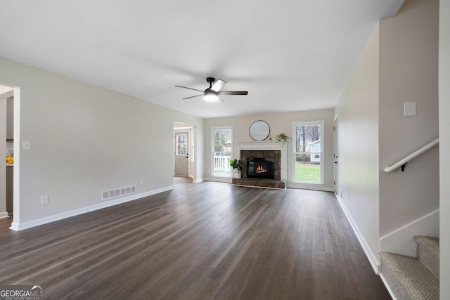 unfurnished living room with a high end fireplace, dark hardwood / wood-style flooring, and ceiling fan