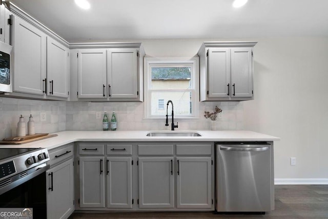 kitchen featuring decorative backsplash, appliances with stainless steel finishes, gray cabinetry, sink, and dark hardwood / wood-style floors