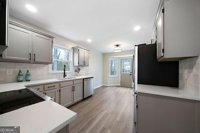 kitchen featuring gray cabinetry, sink, stainless steel appliances, decorative backsplash, and light wood-type flooring