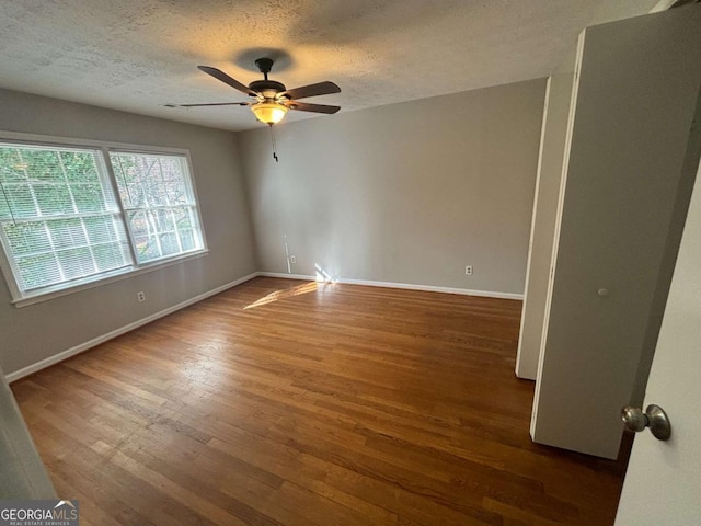 spare room with a textured ceiling, ceiling fan, and dark wood-type flooring