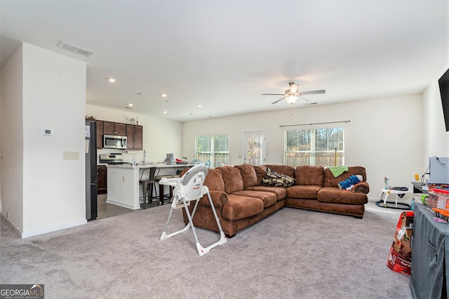 carpeted living room with ceiling fan