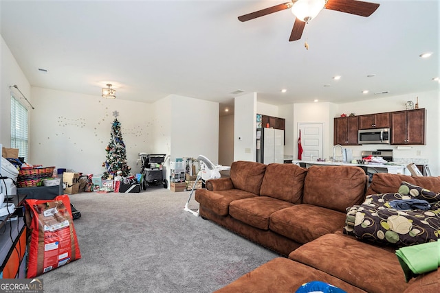 carpeted living room with ceiling fan and sink