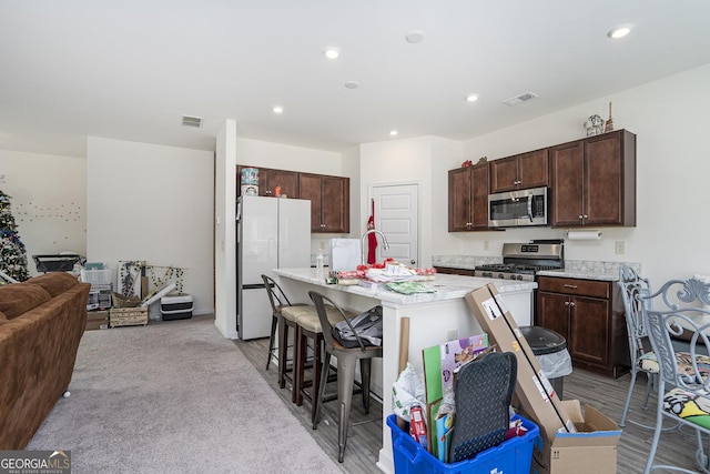 kitchen featuring a breakfast bar, dark brown cabinets, an island with sink, and appliances with stainless steel finishes