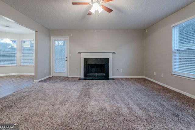 unfurnished living room with ceiling fan, carpet floors, and a textured ceiling