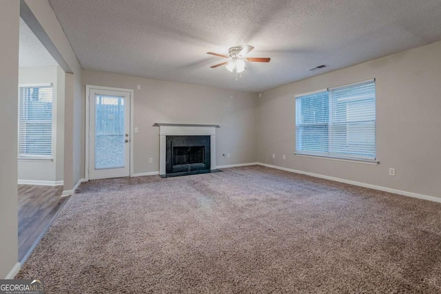 unfurnished living room with carpet, a textured ceiling, and ceiling fan