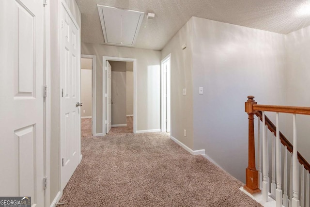 hallway featuring light colored carpet and a textured ceiling