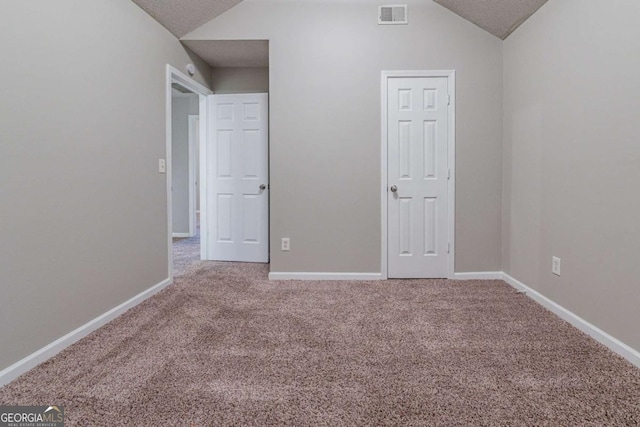 unfurnished bedroom with carpet flooring, a textured ceiling, and vaulted ceiling