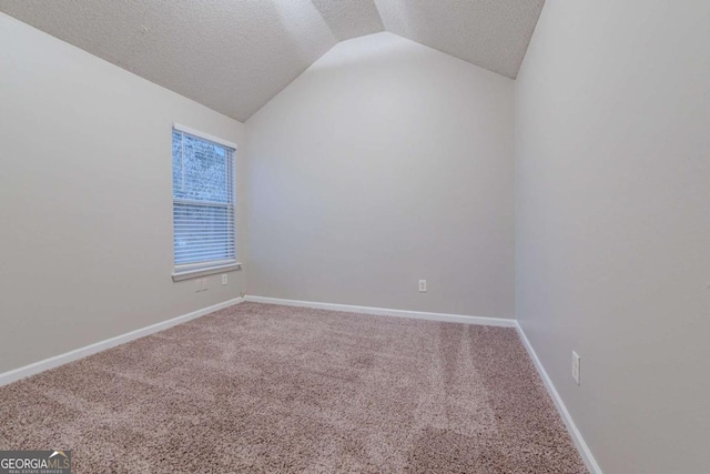 empty room with a textured ceiling, carpet floors, and vaulted ceiling