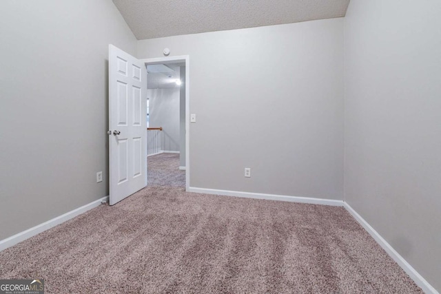 carpeted spare room with lofted ceiling and a textured ceiling