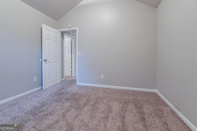 carpeted spare room featuring a textured ceiling and vaulted ceiling