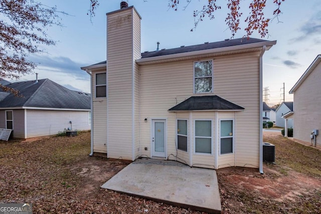 rear view of house with central air condition unit and a patio