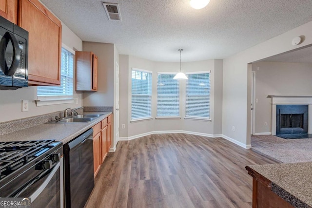 kitchen with black appliances, sink, wood-type flooring, decorative light fixtures, and plenty of natural light