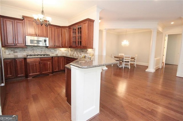 kitchen with stainless steel appliances, a chandelier, dark wood finished floors, a peninsula, and glass insert cabinets