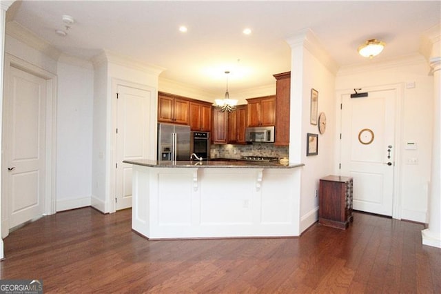 kitchen with stainless steel appliances, a peninsula, baseboards, dark wood finished floors, and tasteful backsplash