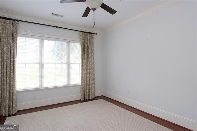 spare room with baseboards, ceiling fan, wood finished floors, ornamental molding, and plenty of natural light
