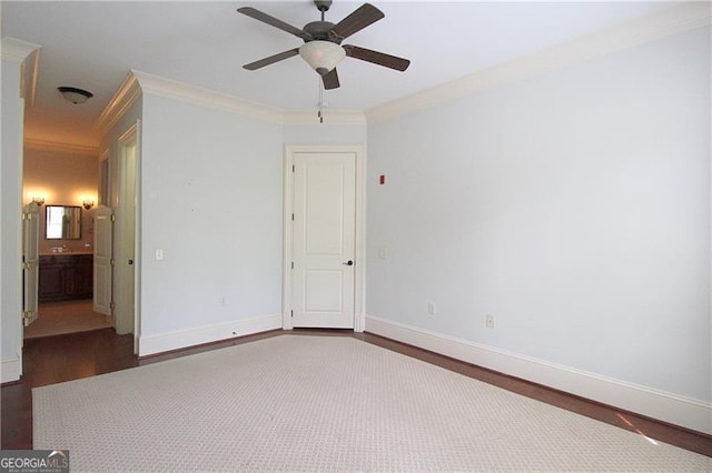unfurnished bedroom with ornamental molding, wood finished floors, baseboards, a ceiling fan, and ensuite bath