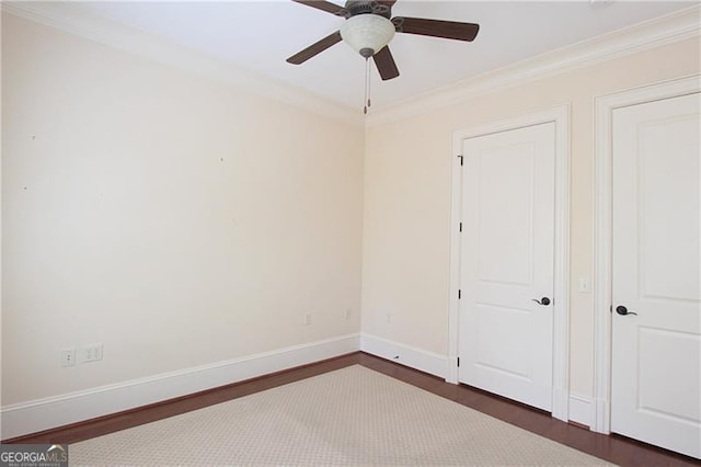 empty room featuring ornamental molding, a ceiling fan, dark wood finished floors, and baseboards