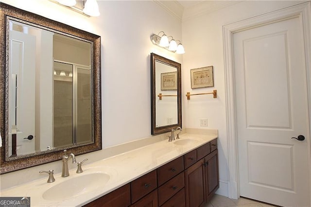 bathroom featuring ornamental molding, double vanity, a shower with shower door, and tile patterned flooring