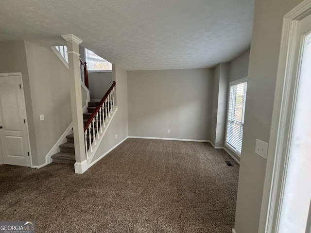 interior space featuring ornate columns, carpet floors, and a textured ceiling