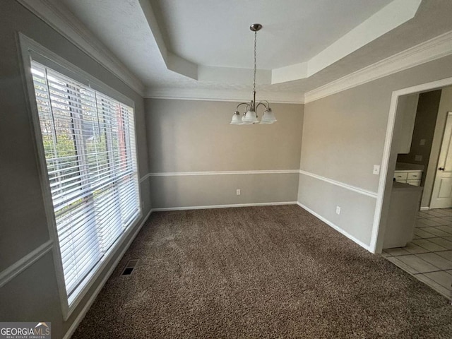 carpeted spare room with a chandelier, ornamental molding, and a tray ceiling