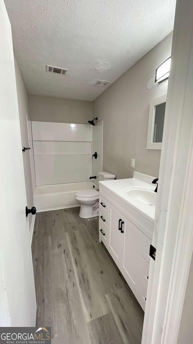 full bathroom with toilet, vanity, a textured ceiling, and hardwood / wood-style flooring