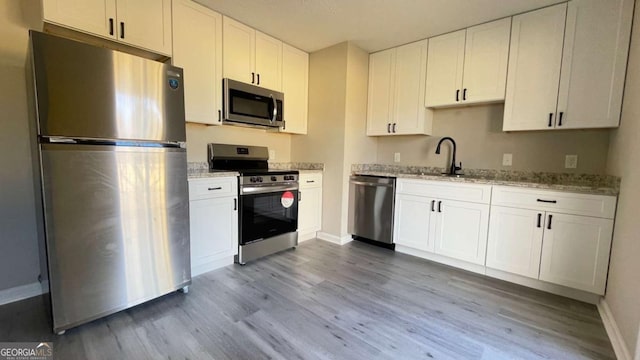 kitchen featuring sink, white cabinetry, stainless steel appliances, and light hardwood / wood-style flooring