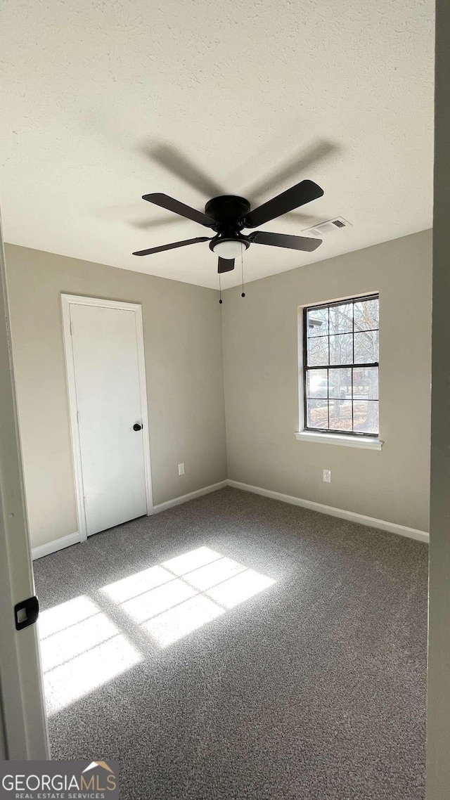 unfurnished room featuring carpet, ceiling fan, and a textured ceiling