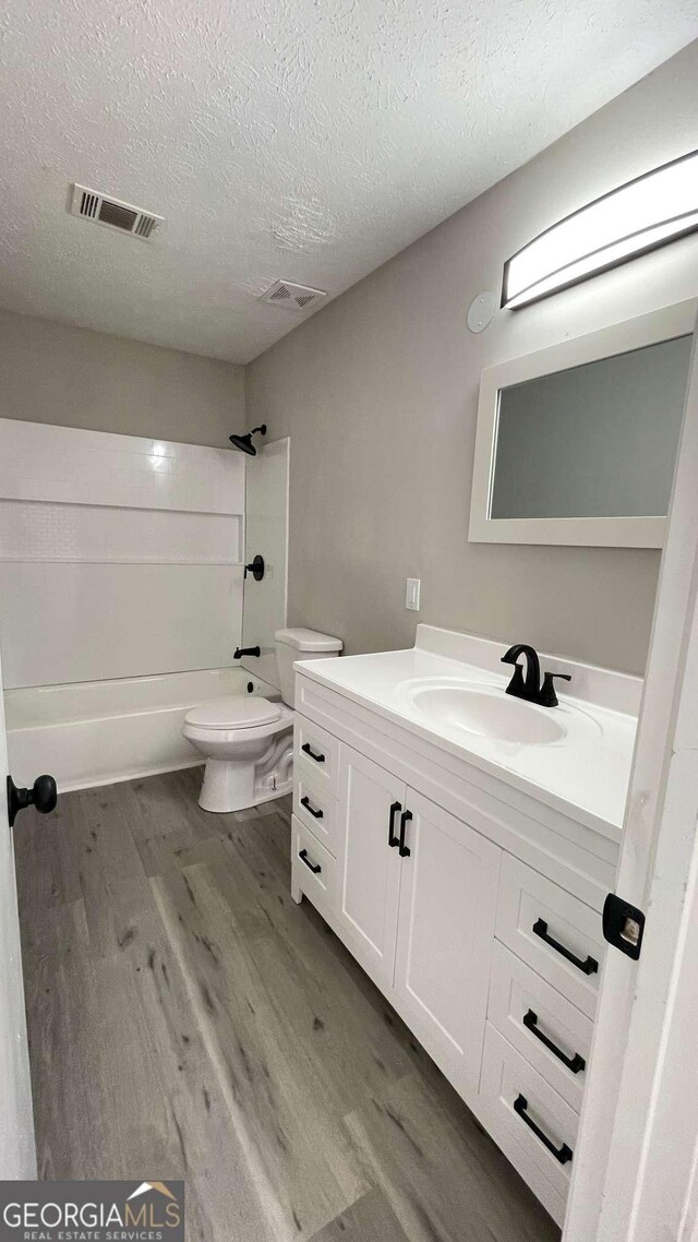 full bathroom featuring vanity, hardwood / wood-style floors, a textured ceiling, and toilet