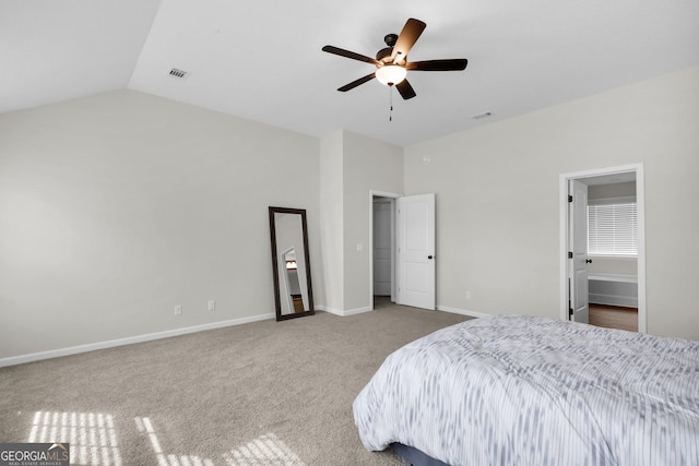 carpeted bedroom with ceiling fan, ensuite bathroom, and vaulted ceiling