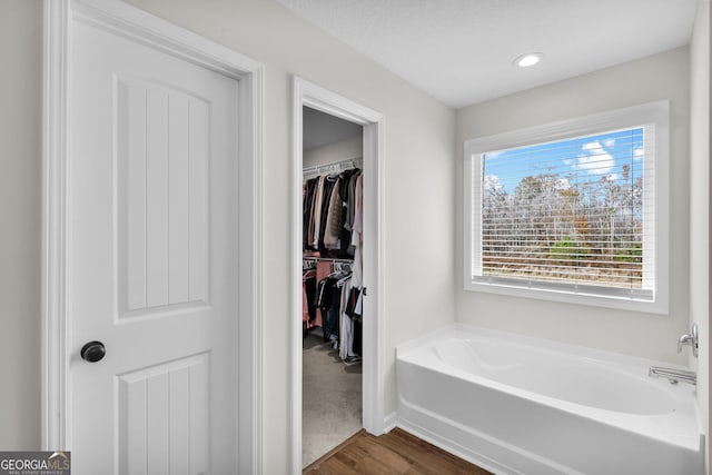 bathroom featuring a tub to relax in, hardwood / wood-style floors, and a textured ceiling