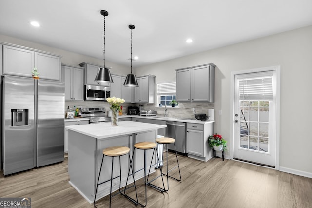 kitchen with a breakfast bar, a center island, light hardwood / wood-style flooring, appliances with stainless steel finishes, and tasteful backsplash