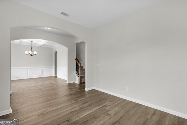 spare room with beamed ceiling, a chandelier, coffered ceiling, and hardwood / wood-style flooring