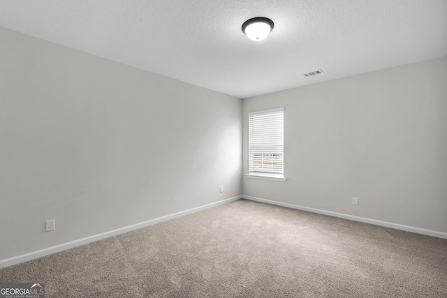 unfurnished room with carpet and a textured ceiling