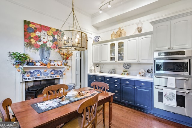 kitchen with white cabinets, double oven, tasteful backsplash, hanging light fixtures, and blue cabinets