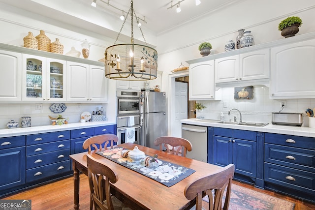 kitchen featuring appliances with stainless steel finishes, blue cabinets, tasteful backsplash, and sink