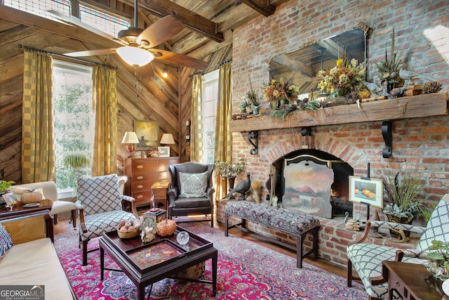 sitting room featuring ceiling fan, a high ceiling, wood walls, and beam ceiling