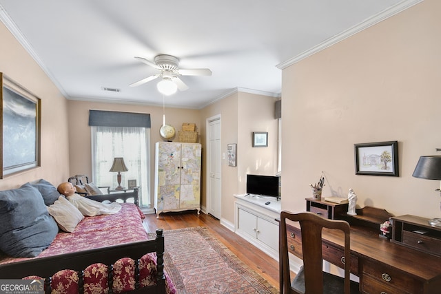 bedroom featuring ceiling fan, ornamental molding, and hardwood / wood-style floors