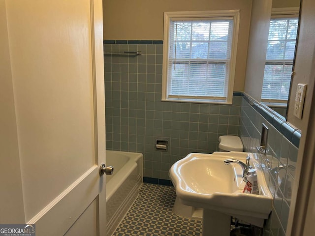 bathroom featuring tile walls, a bathing tub, and sink