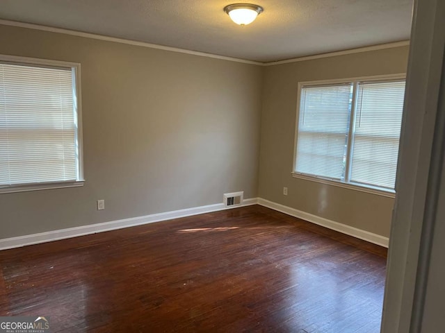 empty room featuring a textured ceiling, ornamental molding, and dark wood-type flooring