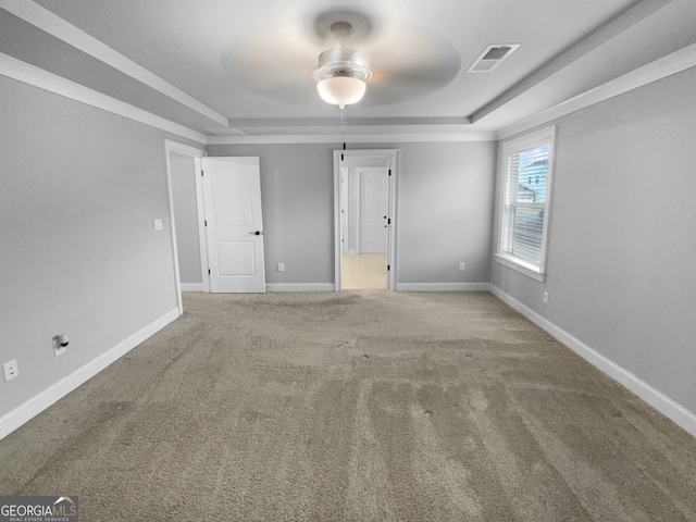 empty room featuring carpet flooring, a raised ceiling, and ceiling fan