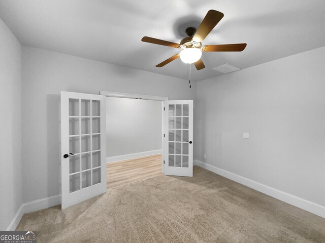 carpeted spare room featuring french doors and ceiling fan