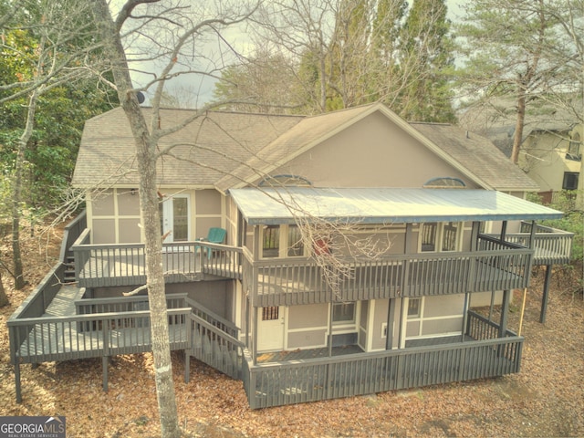 back of house with a deck, a shingled roof, stucco siding, and stairs
