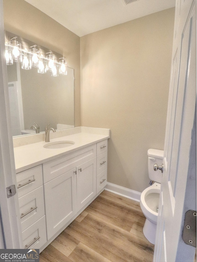 bathroom with vanity, toilet, and wood-type flooring