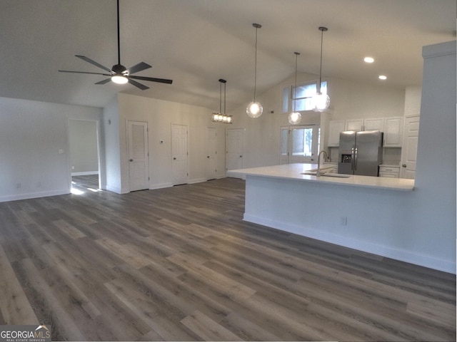kitchen featuring a sink, high vaulted ceiling, open floor plan, stainless steel fridge, and white cabinets
