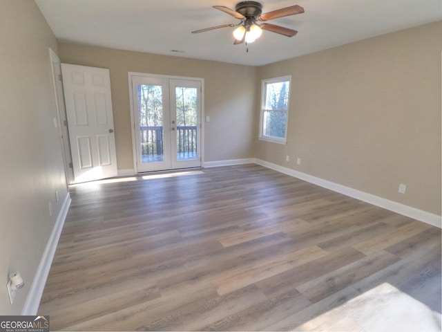 empty room with ceiling fan, baseboards, french doors, and wood finished floors