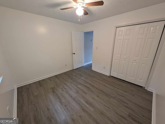 unfurnished bedroom with ceiling fan, a closet, and dark wood-type flooring