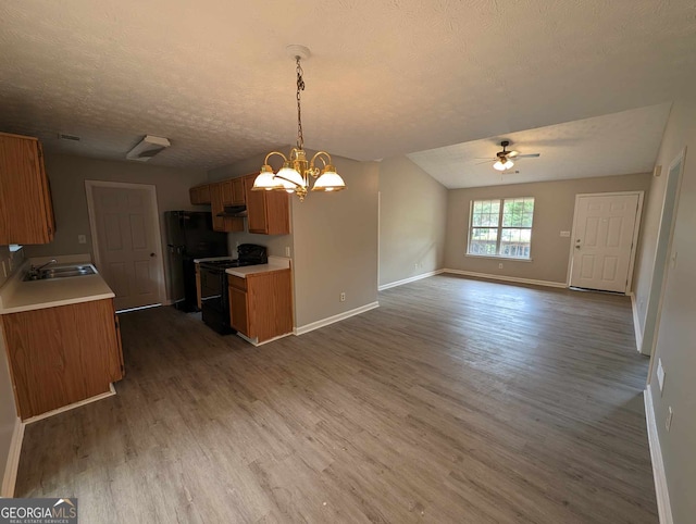 kitchen with hardwood / wood-style floors, black appliances, ceiling fan with notable chandelier, and sink