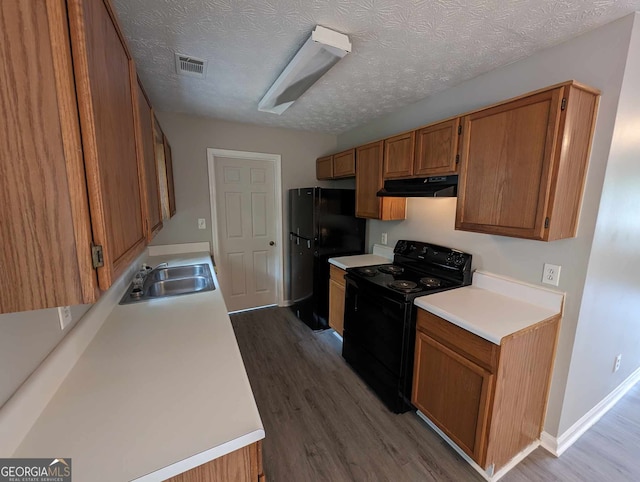 kitchen featuring sink, a textured ceiling, light hardwood / wood-style flooring, and black appliances